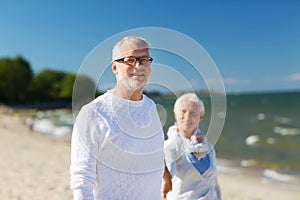Happy senior couple holding hands on summer beach