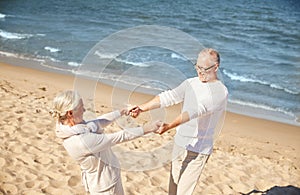 Happy senior couple holding hands on summer beach