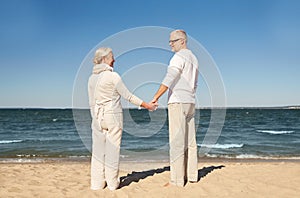 Happy senior couple holding hands summer beach