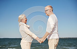 Happy senior couple holding hands summer beach