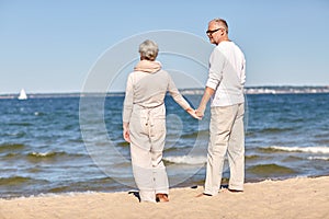 Happy senior couple holding hands summer beach