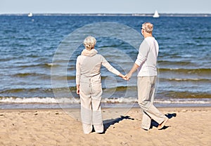 Happy senior couple holding hands summer beach