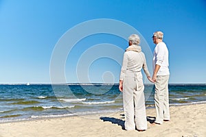 Happy senior couple holding hands summer beach