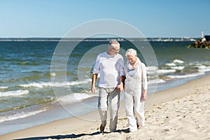 Happy senior couple holding hands on summer beach