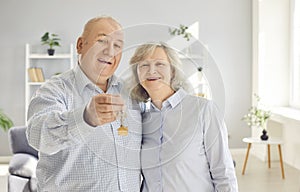 Happy senior couple holding a key in their hands standing in a new apartment on moving day.