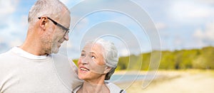 Happy senior couple hugging over beach background