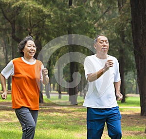 Happy senior couple jogging together in the park