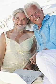 Happy Senior Couple with Laptop Computer on Beach