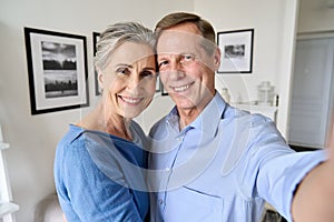 Happy senior couple looking at camera taking selfie portrait, camera view.