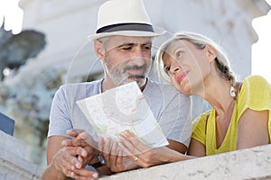 happy senior couple looking for directions using map