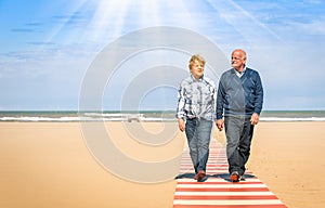 Happy senior couple in love walking hand in hand at the beach