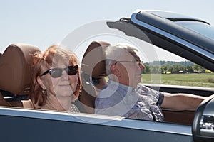 Happy senior couple with a luxury convertible car
