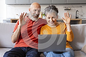 Happy Senior Couple Making Video Call With Laptop At Home