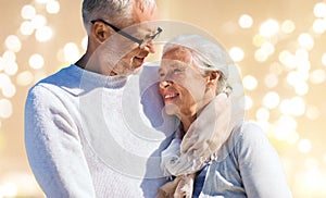 Happy senior couple over festive lights background