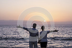 Happy senior couple people in love enjoy a sunset on the ocean holding hands - Ã±pve and relationship elderly summer holiday