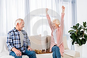 happy senior couple playing chess at home