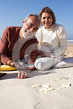 Happy senior couple playing dominoes at seashore