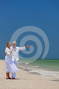 Happy Senior Couple Pointing Smiling on Tropical Beach