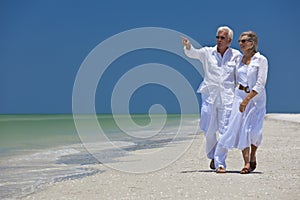Happy Senior Couple Pointing To Sea on Beach
