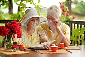 Happy senior couple reading book while drinking coffee