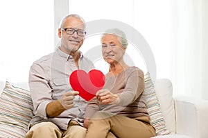 Happy senior couple with red heart shape at home