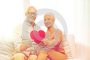 Happy senior couple with red heart shape at home