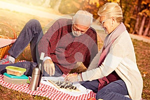 Happy senior couple relaxing in park playing chess together