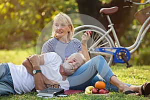 Happy senior couple relaxing in park  together. old people sitting on grass in the summer park . Elderly resting .mature photo