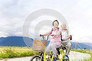 Happy Senior Couple Riding Bicycle on country road