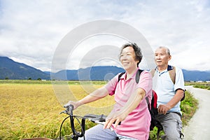 Happy Senior Couple Riding Bicycle on country road