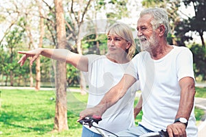 Happy senior couple riding a bicycle in the park