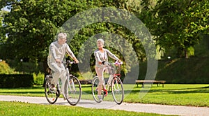 Happy senior couple riding bicycles at summer park