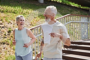 Happy senior couple running with delight at the summer park and trying to keep body fit