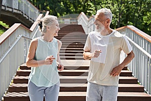 Happy senior couple running with delight at the summer park and trying to keep body fit