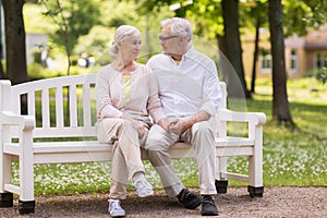 Happy senior couple sitting on bench at park
