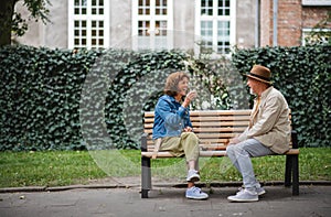 Happy senior couple sitting on bench and playing chess outdoors in park.