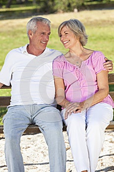 Happy Senior Couple Sitting on Bench in Sunshine