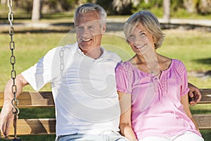 Happy Senior Couple Sitting on Bench in Sunshine