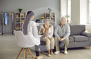 Happy senior couple sitting on couch at home and talking to their family practitioner