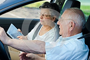 Happy senior couple sitting inside car