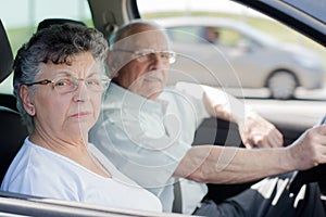 Happy senior couple sitting inside their car