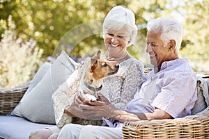 Happy senior couple sitting with a pet dog in the garden