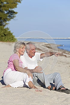 Happy Senior Couple Sitting Pointing on Beach