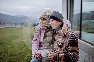 Happy senior couple sitting on terrace and drinking coffee together.