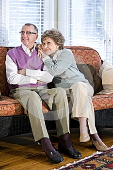 Happy senior couple sitting together on couch