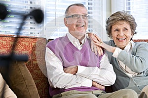 Happy senior couple sitting together on couch