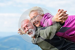 Happy senior couple smiling outdoors in nature. Grandparents, autumn.