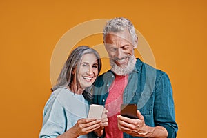 Happy senior couple smiling and using smart phones and smiling