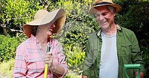 Happy senior couple standing with gardening tools 4k