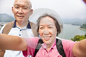 Happy senior couple taking picture with smart phone selfie